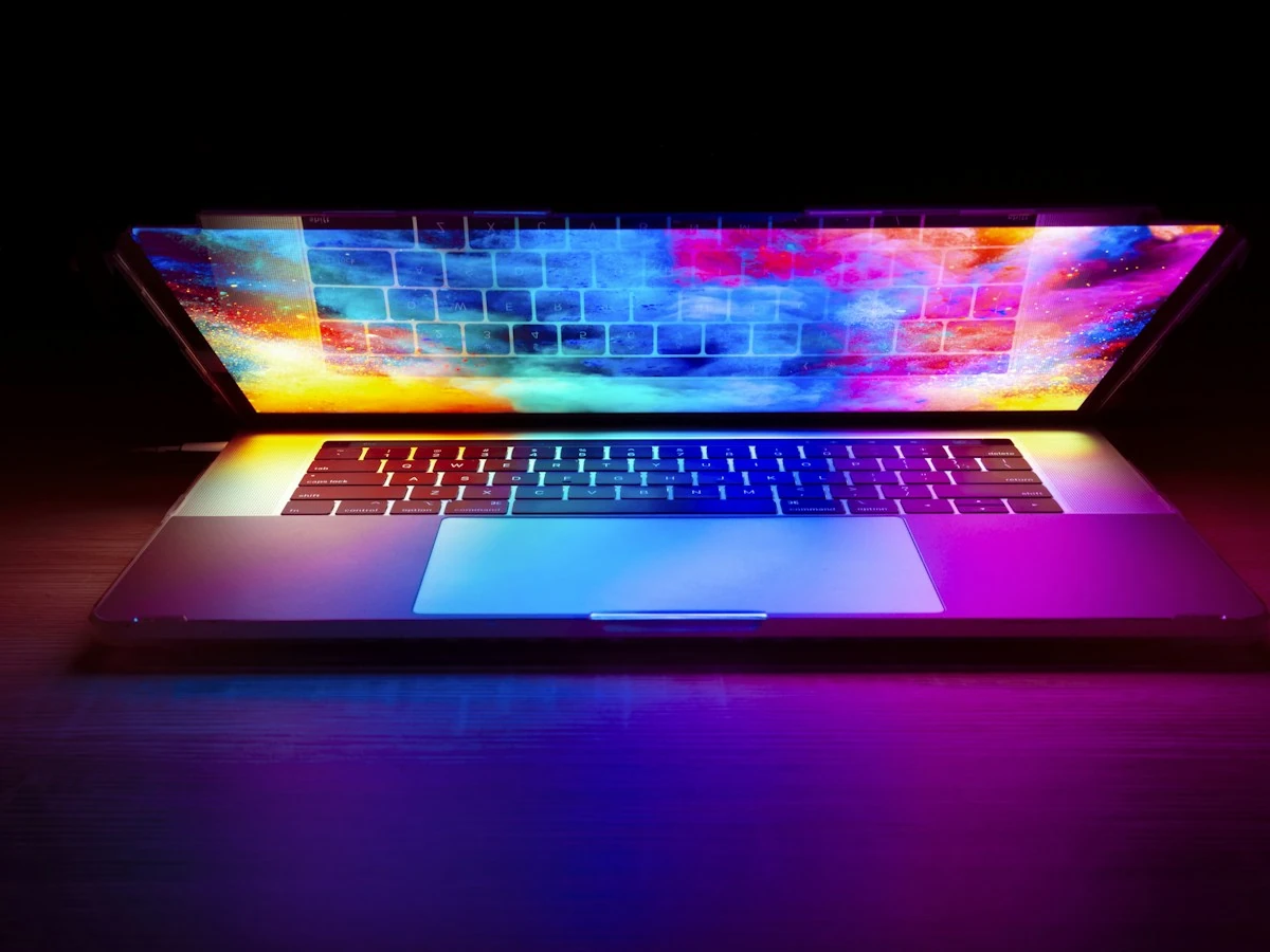 AnimateImage laptop with a bright multicolor screen on a dark wooden desk