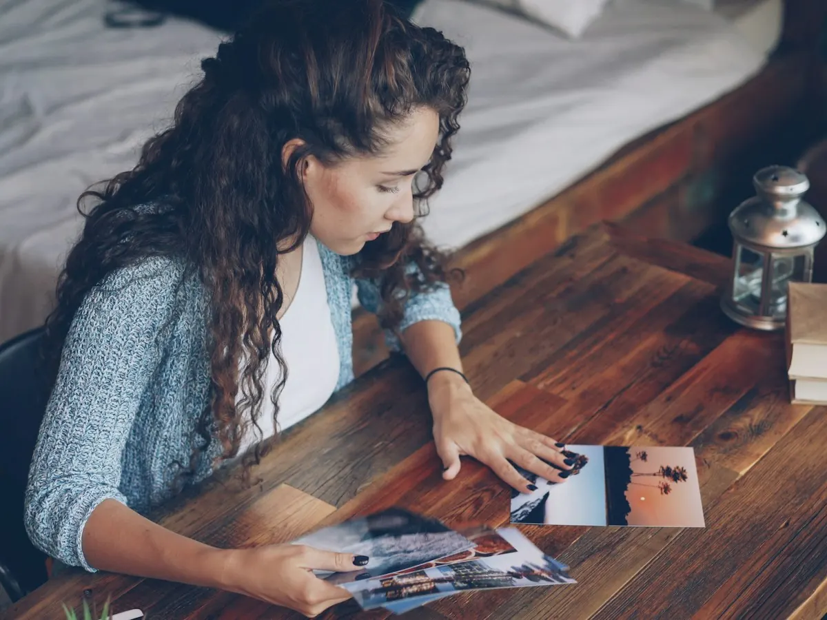 AnimateImage scene: woman sorting printed photos on a wooden table
